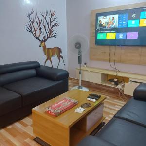 a living room with a couch and a table and a tv at Le séjour fruité in Ouidah