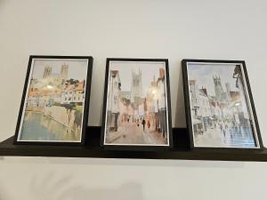 drie ingelijste foto's op een plank aan een muur bij Pretty City Centre Cottage in Hackington +2 foto's