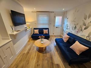 een woonkamer met een blauwe bank en een tafel bij Pretty City Centre Cottage in Hackington
