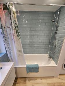 een badkamer met een bad en een douche bij Pretty City Centre Cottage in Hackington