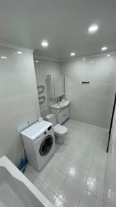 een badkamer met toilet en wasmachine bij БЦ Алматы, иманова-валиханова in Astana +5 foto's