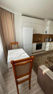 een keuken met een tafel en een witte koelkast bij БЦ Алматы, иманова-валиханова in Astana