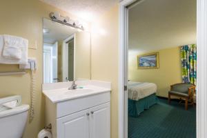 un bagno con lavandino, specchio e letto di Peppertree By The Sea a Myrtle Beach