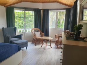 a bedroom with a bed and chairs and windows at Villa Magia Verde in Furnas