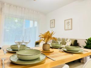 a wooden table with plates and wine glasses on it at L'Ecrin Douceur - Parking privée & Proche gare in Sainte-Savine