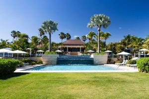 a swimming pool with a house and palm trees at Just a few minutes walking to the Beach Club in Sabana
