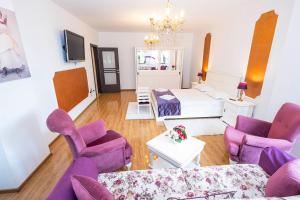 a living room with purple chairs and a couch at Noblesse Suite in Galaţi