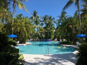 una piscina con palmeras y sombrillas azules en Golf Villa, en Key West