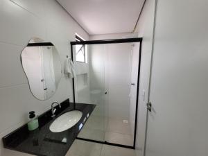 a bathroom with a sink and a mirror and a shower at Perto da praia espaço amplo terraço, churrasqueira in Pontal do Paraná +20 photos