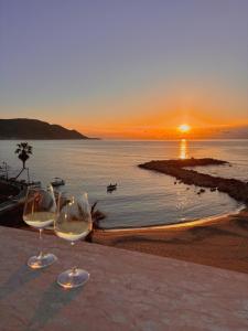 two wine glasses sitting on a table with the sunset at Marger Apartments in Santa Maria di Castellabate