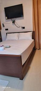 une chambre avec un lit avec une télévision au mur dans l'établissement Migela Restaurant & Rooms, à Walliwala East