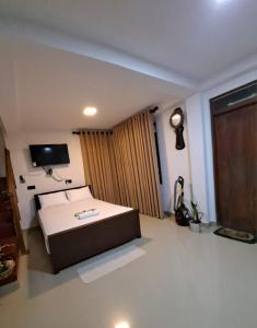 une chambre avec un lit et une télévision au mur dans l'établissement Migela Restaurant & Rooms, à Walliwala East