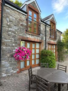 a stone building with a table and flowers in front of it at Hael Farm Cottage in Swansea