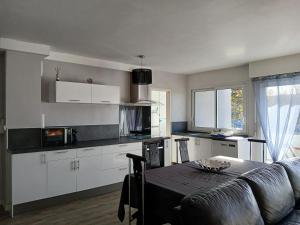 une cuisine avec des armoires blanches, une table et un canapé dans l'établissement Charmant T3 aux portes de Bordeaux - 2 chambres, à Lormont