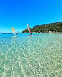 two people are windsurfing in the water on a beach at THALASSA Beach Poetto in Cagliari +22 photos