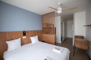 a bedroom with a large white bed with a ceiling fan at Ecla Paris Villejuif in Villejuif