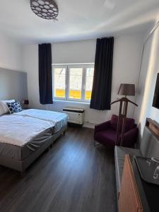 a bedroom with a bed and a chair and windows at Pécs Centrum Apartman in Pécs