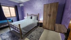 a purple bedroom with a bed and a wooden door at Appartement C à 7 min de l’aéroport de Marrakech in Marrakech