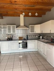a kitchen with white cabinets and a stove top oven at Vue panoramique & jacuzzi privé in Saint-Hilaire +14 photos