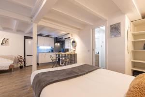 a bedroom with a white bed and a kitchen at Canals by Unik Vacation in Tarragona