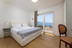 a white bedroom with a bed and a balcony at Villa Opera in Povile +68 photos
