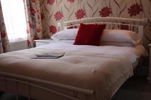 a bedroom with a white bed with a red pillow at Chapter Two Bar in Malton +5 photos