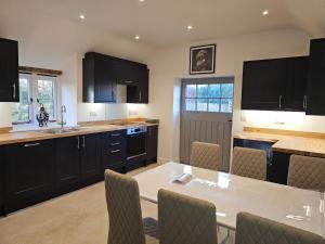 Una cocina con gabinetes negros y una mesa y sillas. en Sleeps 12, Stunning, Dog Friendly, Hot Tub, Rural, en Nether Stowey
