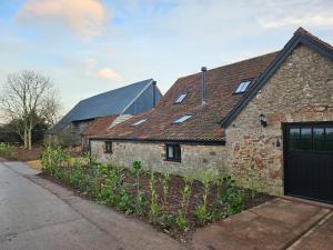 una vieja casa de ladrillo con un garaje negro en Sleeps 12, Stunning, Dog Friendly, Hot Tub, Rural, en Nether Stowey