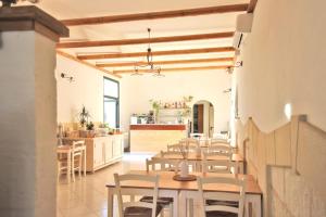 a dining room with tables and chairs and a kitchen at Agriturismo Antares in San Foca