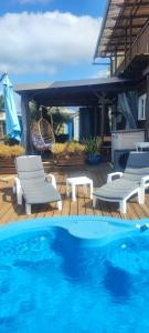 a pool with two chairs and a table and a house at Au doux Tamarin des hauts in Le Tampon +13 photos