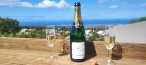 a bottle of wine and two glasses on a table at Au doux Tamarin des hauts in Le Tampon