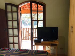 a bedroom with a television on a table next to a window at Chalé Recanto Derrico in Santo Antônio do Pinhal