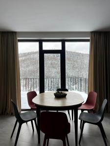 Un comedor con mesa y sillas y una gran ventana. en Chalet Panorama (Апартаменти), en Bukovel 117 fotos más