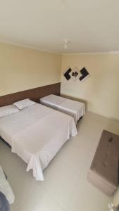 two beds in a hotel room with white walls at Casa de temporada em Prado-BA in Prado