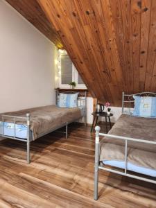 two beds in a room with a wooden ceiling at Pod Czaplą in Warsaw