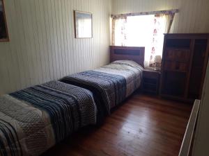 two beds in a small room with a window at La Posada del Colono in Puerto Clocker