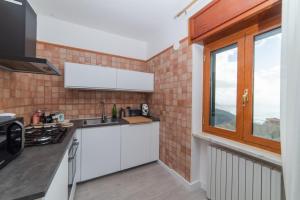 a kitchen with white cabinets and a window at Seaview, Mountains & Relax with TWO Private Pools - Rifugio Dorotea in Salerno