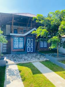 a house with blue and white doors and trees at Airport Accommodation in Maduwa