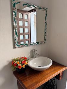 a bathroom sink with a mirror and flowers on a wooden counter at Casa matamoros in Oaxaca City +10 photos