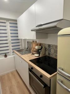 eine Küche mit weißen Schränken und einer Arbeitsplatte in der Unterkunft Appartement Cozy in Avesnes-sur-Helpe