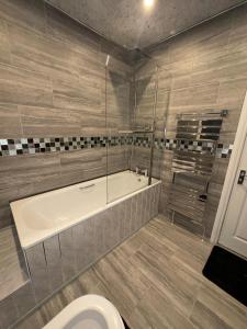 a bathroom with a bath tub and a toilet at Luxxe House with Hot tub and Pool table in Uxbridge +54 photos