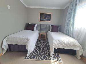 a bedroom with two beds and a window and a rug at Kaabo in Johannesburg