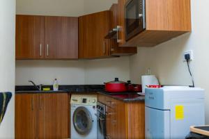 Aspire Tower - Spacious One Bedroom Apartment في المنامة: مطبخ مع خزائن خشبية وغسالة ملابس