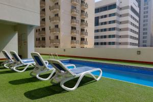 Aspire Tower - Spacious One Bedroom Apartment في المنامة: صف من كراسي صالة الكراسي بجانب مسبح