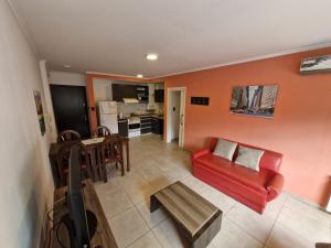 Una sala de estar con un sofá rojo y una mesa. en Departamento VCP Costanera, en Villa Carlos Paz