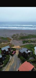Luftaufnahme eines Strandes mit Häusern und dem Meer in der Unterkunft cabaña punta de lobos in Pichilemu