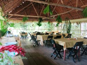 a dining room with tables and chairs and plants at Amazon Golden Snake Lodge in Santa Teresa