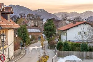 a street in a village with mountains in the background at LIBORIA: Stylisches Haus; Sauna ; 4min zum See in Seehausen am Staffelsee