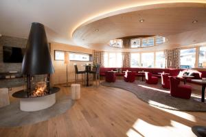 - un salon avec une cheminée et des chaises rouges dans l'établissement Hotel Walserstube, à Warth am Arlberg