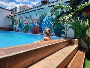 a young child sitting in a swimming pool with a mural at Travelero Hostel & Tours in Santa Cruz de la Sierra